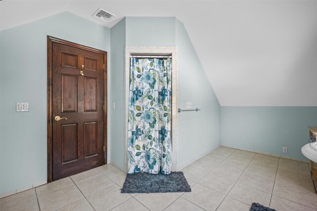 full bathroom with a shower with shower curtain, tile patterned flooring, visible vents, and vaulted ceiling
