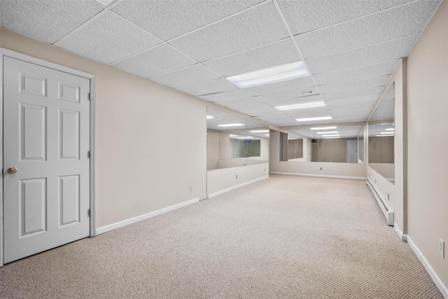 finished basement with baseboards, a paneled ceiling, carpet, and baseboard heating