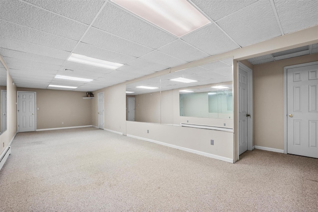 finished basement featuring a paneled ceiling, carpet flooring, and baseboards