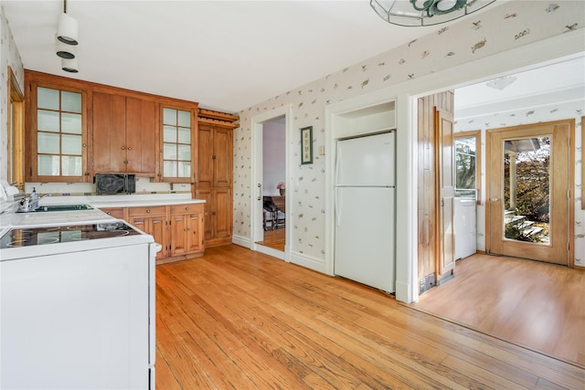 kitchen with light hardwood / wood-style floors, washer / dryer, white appliances, and sink