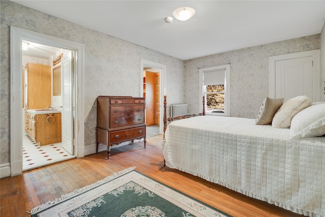 bedroom featuring wood-type flooring, connected bathroom, and radiator heating unit