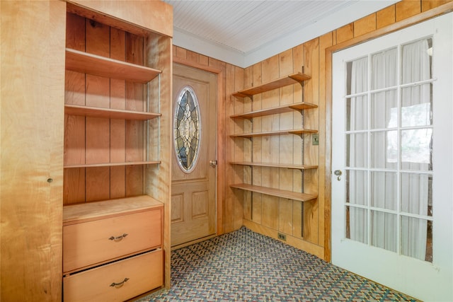 interior space with ornamental molding and wooden walls