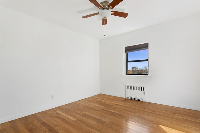 spare room with ceiling fan, radiator heating unit, and hardwood / wood-style flooring