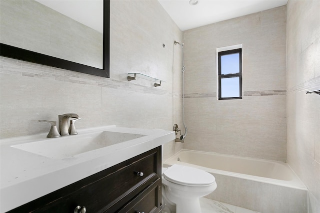 full bathroom with vanity, toilet, tile walls, and tiled shower / bath