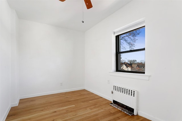 unfurnished room featuring radiator, ceiling fan, and light wood-type flooring