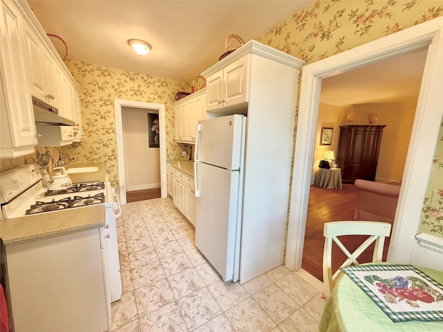 kitchen with white cabinets, white appliances, and sink