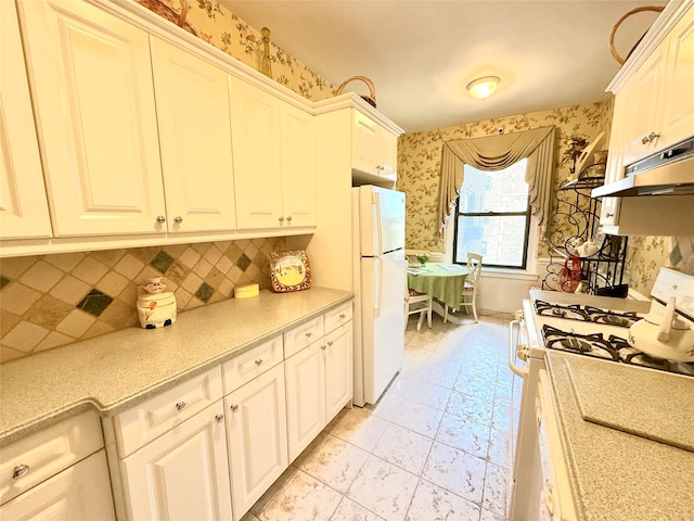 kitchen with light tile patterned floors, white appliances, white cabinetry, and backsplash