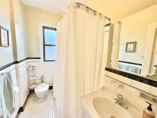 bathroom with tile patterned floors, toilet, tile walls, and sink