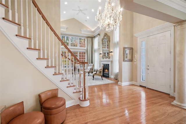 entryway featuring high vaulted ceiling, light hardwood / wood-style floors, and ceiling fan with notable chandelier