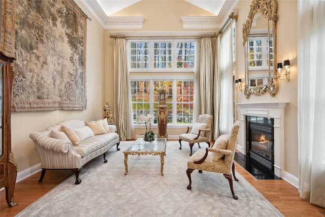 sitting room featuring crown molding, a towering ceiling, and hardwood / wood-style flooring