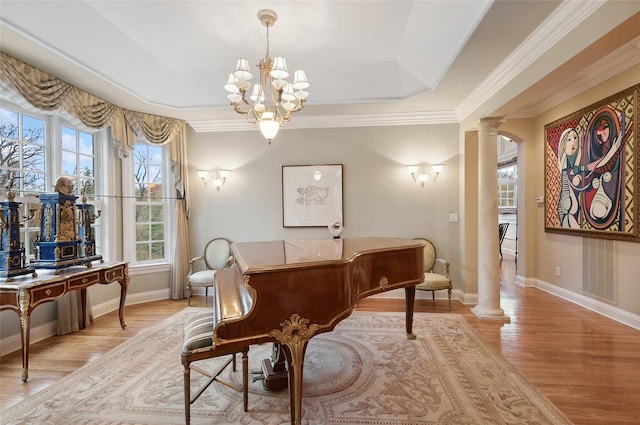 miscellaneous room with light wood-type flooring, decorative columns, a raised ceiling, and a notable chandelier