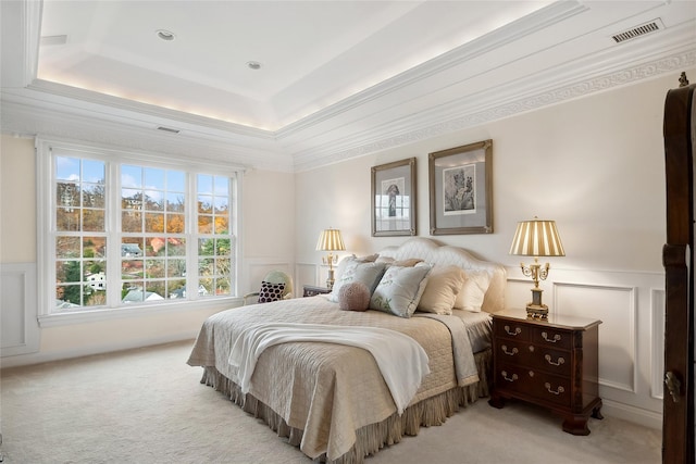 carpeted bedroom with a tray ceiling and ornamental molding