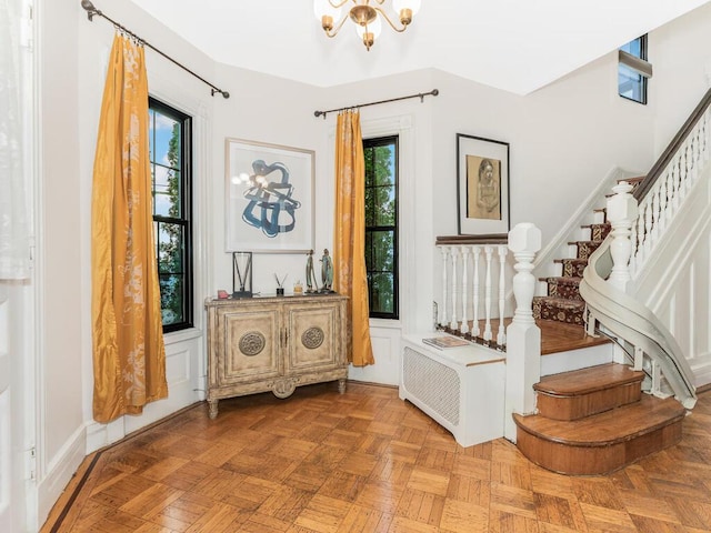 foyer with plenty of natural light, light parquet floors, and a notable chandelier