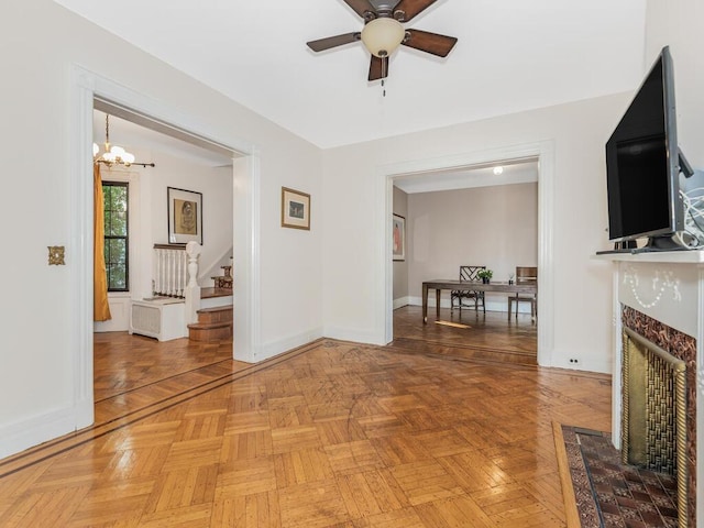 unfurnished living room with ceiling fan with notable chandelier and parquet floors