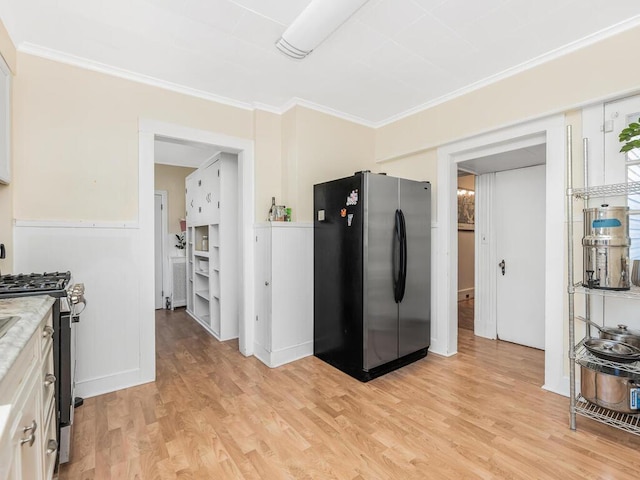 kitchen with white cabinetry, light hardwood / wood-style flooring, ornamental molding, and appliances with stainless steel finishes