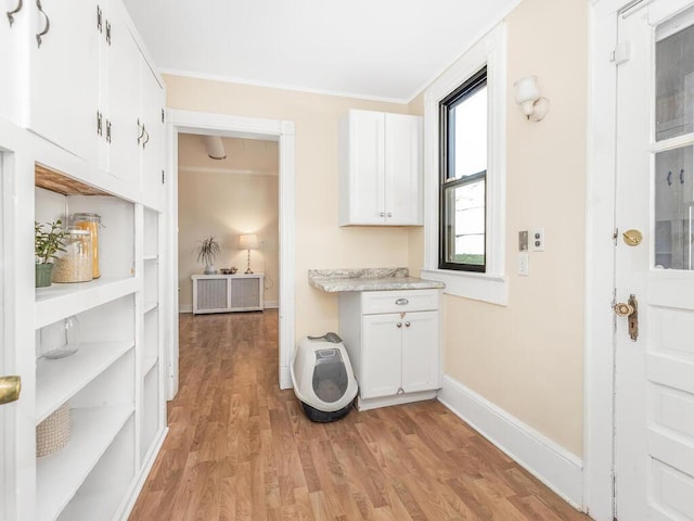 kitchen featuring white cabinets, light hardwood / wood-style floors, and ornamental molding