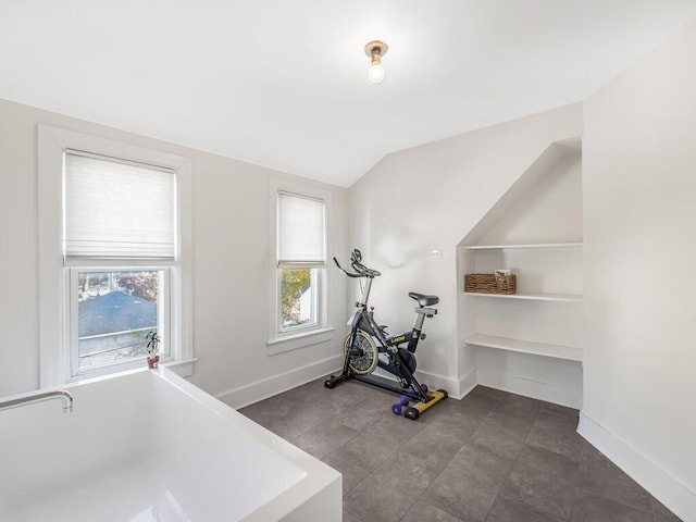 workout room featuring dark tile patterned flooring and vaulted ceiling