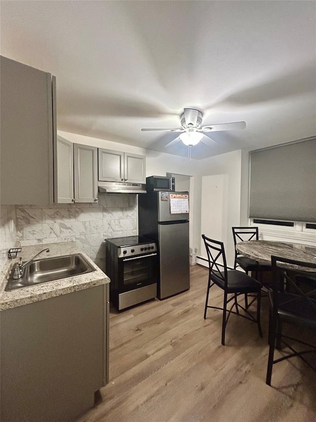 kitchen featuring sink, tasteful backsplash, light hardwood / wood-style floors, gray cabinets, and appliances with stainless steel finishes