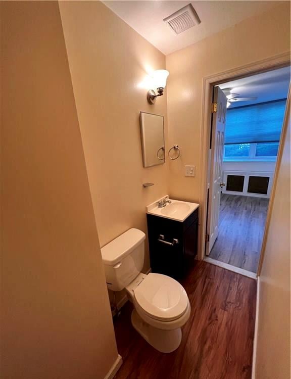 bathroom with toilet, vanity, and hardwood / wood-style flooring