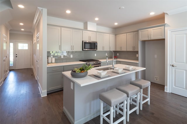 kitchen featuring dark hardwood / wood-style flooring, a kitchen island with sink, sink, and stainless steel appliances