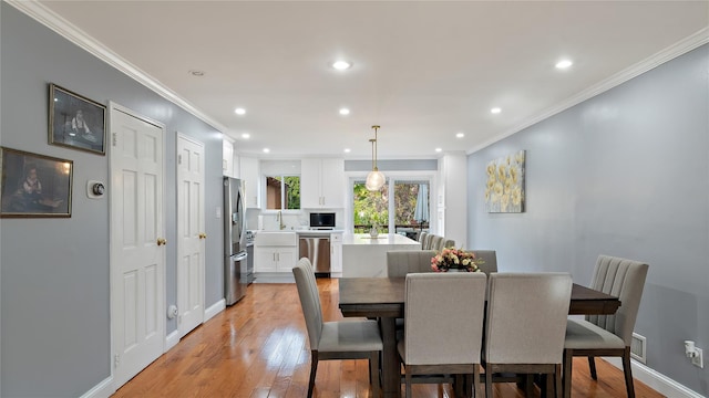 dining area with sink, crown molding, and light hardwood / wood-style flooring