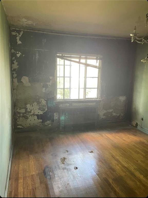 unfurnished room featuring a chandelier and dark hardwood / wood-style floors