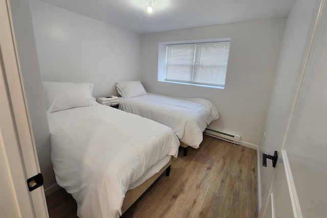 bedroom with light wood-type flooring and a baseboard heating unit