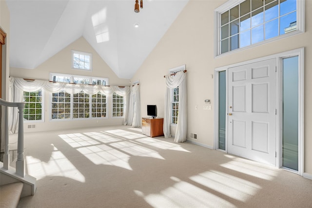 unfurnished living room featuring a wealth of natural light, light colored carpet, and high vaulted ceiling