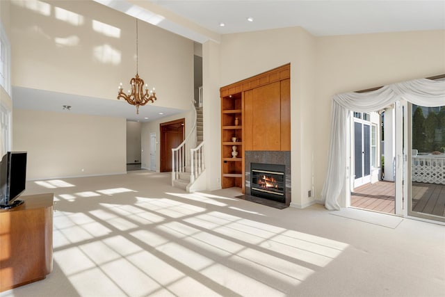 unfurnished living room with light carpet, high vaulted ceiling, and a chandelier