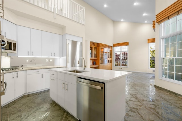 kitchen with stainless steel appliances, sink, a center island with sink, high vaulted ceiling, and white cabinets