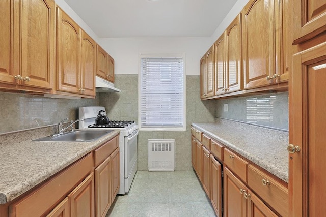 kitchen with sink, light tile patterned flooring, white range with gas stovetop, and tile walls