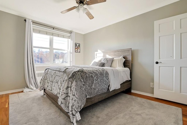 bedroom with hardwood / wood-style floors, ceiling fan, and ornamental molding