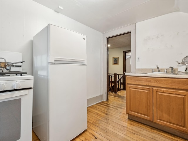 kitchen featuring white appliances, sink, and light hardwood / wood-style flooring