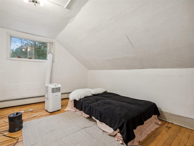 bedroom featuring lofted ceiling, light hardwood / wood-style floors, and a baseboard heating unit