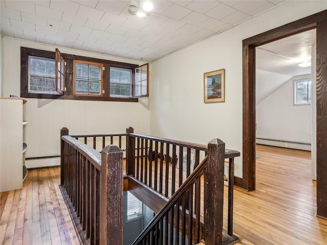 corridor featuring hardwood / wood-style floors, plenty of natural light, and a baseboard heating unit