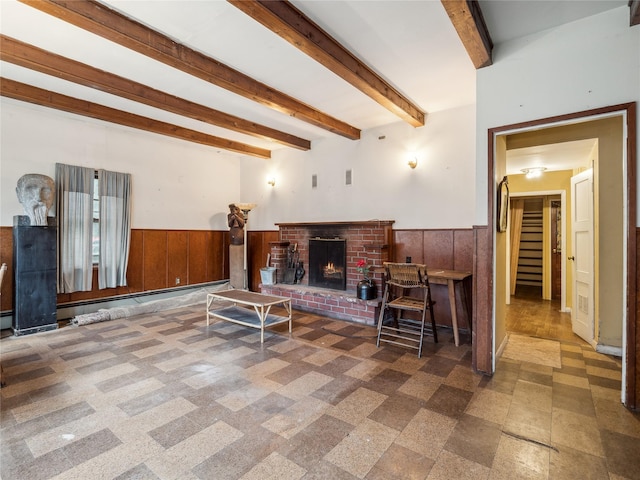 living room with beam ceiling, wooden walls, and a brick fireplace