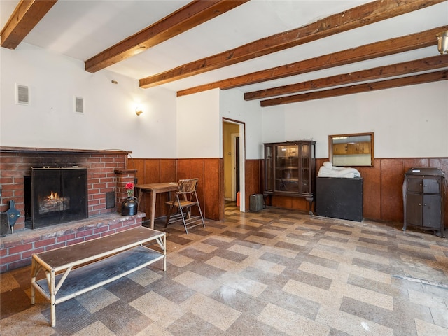 living room featuring beam ceiling, a fireplace, and wooden walls