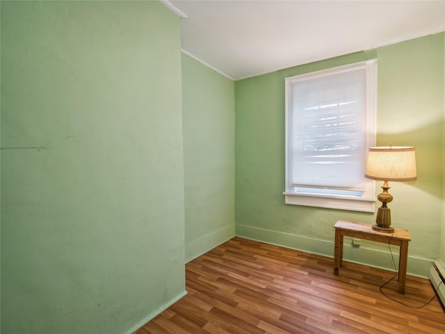 empty room featuring hardwood / wood-style floors and a baseboard heating unit