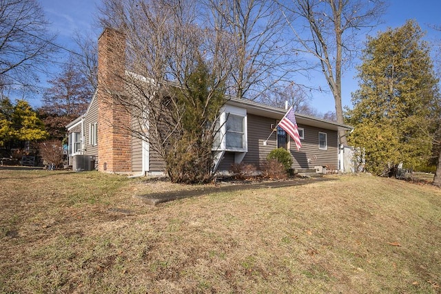 view of side of home with a yard and central AC