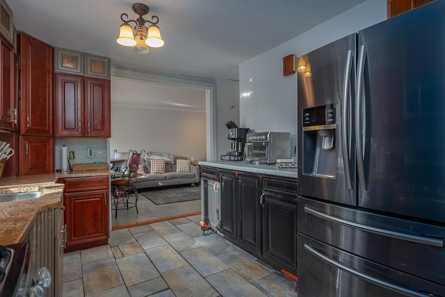 kitchen with range, tasteful backsplash, light stone counters, stainless steel refrigerator with ice dispenser, and a chandelier