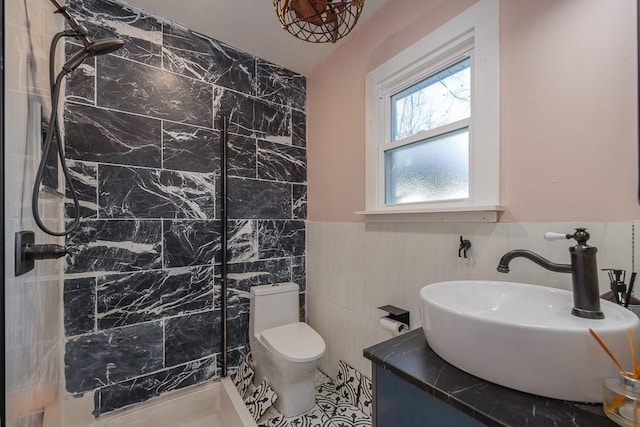 bathroom featuring tile walls, toilet, vanity, and a tile shower