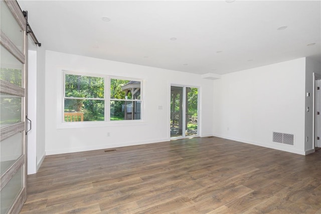 empty room featuring a barn door and dark hardwood / wood-style floors