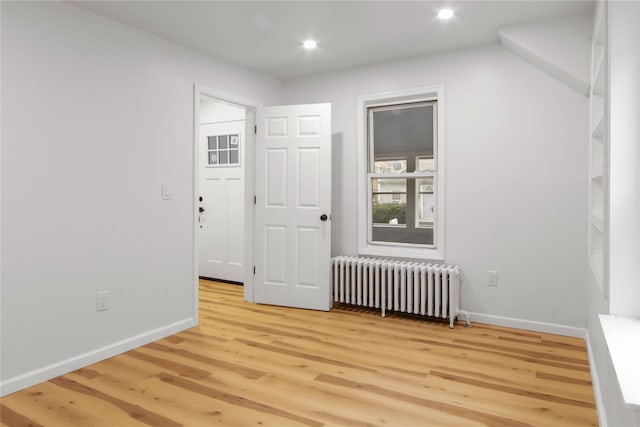 unfurnished room featuring radiator heating unit and light wood-type flooring