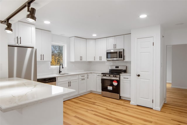 kitchen featuring sink, white cabinetry, stainless steel appliances, and hanging light fixtures