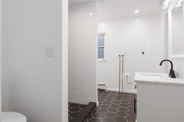 bathroom featuring vanity, a baseboard heating unit, tile patterned flooring, toilet, and a tile shower