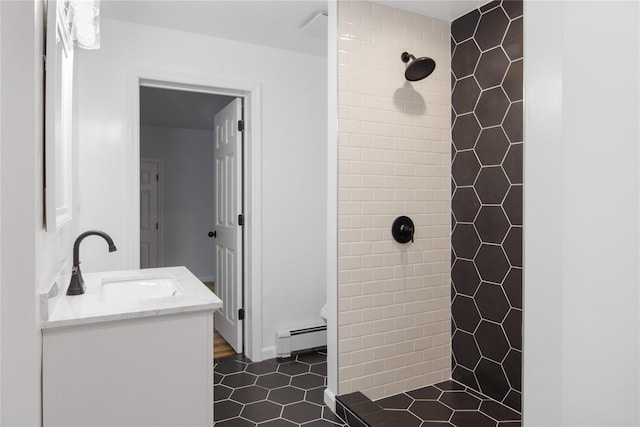 bathroom featuring tile patterned floors, vanity, a tile shower, and baseboard heating