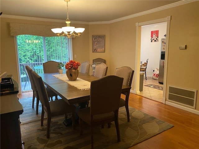 dining space with wood-type flooring, an inviting chandelier, and ornamental molding