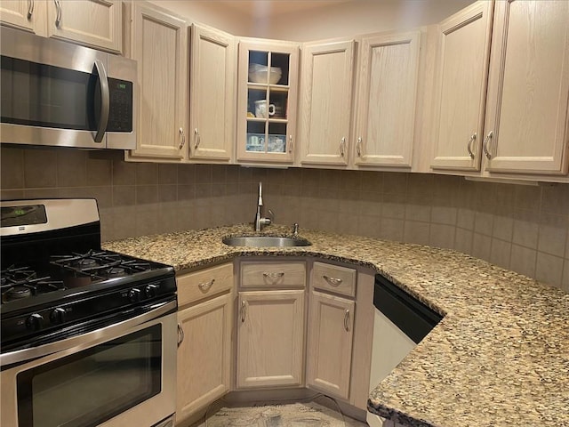 kitchen featuring decorative backsplash, stainless steel appliances, light stone countertops, and sink