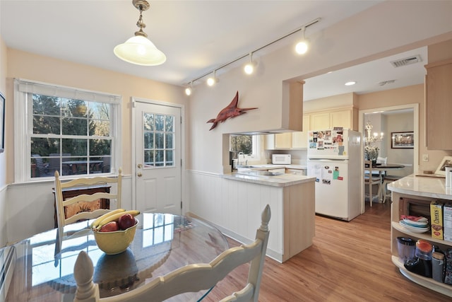 dining room with light wood finished floors, visible vents, and wainscoting