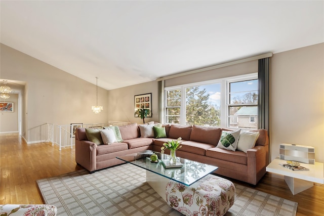 living room with a notable chandelier, baseboards, light wood-style floors, and vaulted ceiling